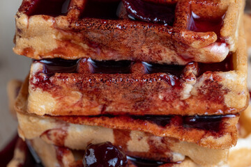 soft waffles with red cherry jam on a serving board