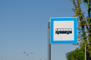 Bus stop sign on a metal pole with a sky in the background