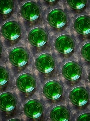 A creative pattern from the top view of shots with absinthe on a black concrete background. Abstract background of glasses with a green bitter drink from wormwood.