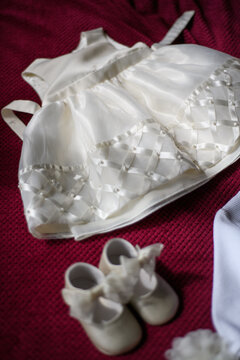Overhead view of a christening dress and christening shoes on a bed