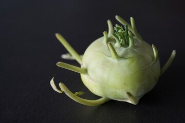 Close up of a green kohlrabi with its strange tentacles. Black background