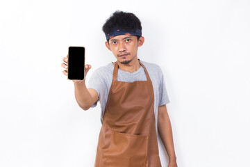 Happy joyful young asian man barista bartender or waitress demonstrating mobile cell phone on white...