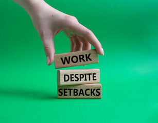 Work despite setbacks symbol. Wooden blocks with words Work despite setbacks. Beautiful green background. Businessman hand. Business and Work despite setbacks concept. Copy space.