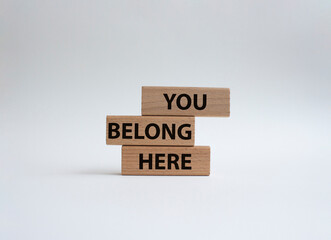 You belong here symbol. Wooden blocks with words You belong here. Beautiful white background. Business and You belong here setbacks concept. Copy space.
