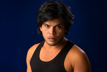 Portrait of a young man posing and showing his muscular body. The concept of a healthy lifestyle on blue background.