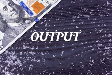 OUTPUT - word (text) on a dark wooden background, money, dollars and snow. Business concept (copy space).