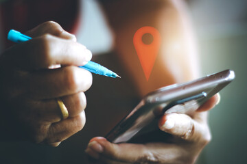 Woman holding a pen texting a check-in point on her smartphone