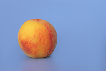 Yellow ripe peach close-up on a bed blue background, space for copying