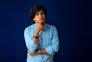 Portrait of a young man thinking on a dark background