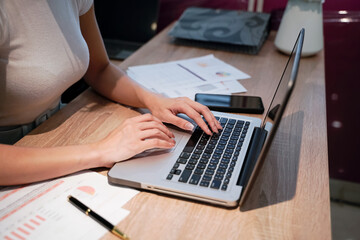 Fototapeta premium Businesswoman sitting at a desk, business woman's hands resting on laptop computer keyboard.