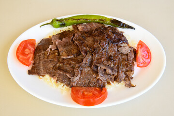 Turkish and Arabic Traditional Ramadan doner kebab with tasty tomato sauce and rice or turkish pilav in white plate on wood table background. ( , Iskender, ekmek arasi pilav ustu doner, doner durum )