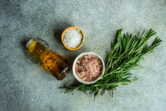 Overhead view of salt, himalayan pink salt, rosemary and chilli oil on a  table