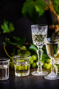 Assorted glasses of Georgian chacha brandy on a table with bunches of green grapes