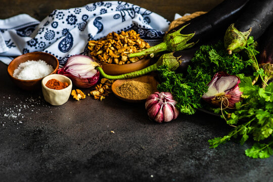 Ingredients for Georgian eggplant and walnut rolls (Badrizhan nigzvit) on a table with a traditional Georgian tablecloth