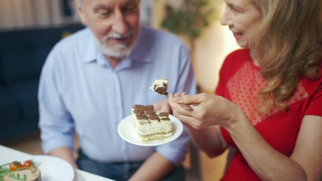 Wife feeding cake to her husband, happy married couple, romantic dinner