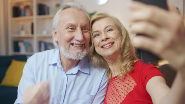 Smiling senior husband and wife taking selfie on smartphone, special occasion