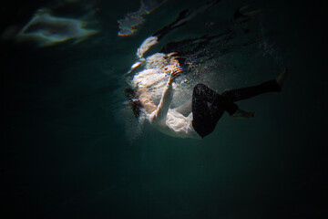 Beautiful underwater shooting, guy in white shirt and pants has fallen under the water and...