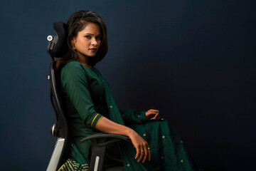 Naklejka premium A beautiful girl sitting on an executive chair and posing.