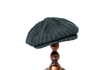 Detail of a classic eight-panel newsboy hat, in black with pattern herringbone tweed fabric set against a bronze head mannequin on a white background