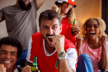 Football fans having fun cheering and celebrating while watching game on TV