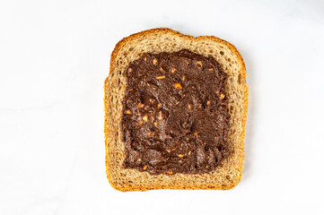 Slice of open sandwiche from wholegrain bread with chocolate crunchy almond butter, healthy snack option