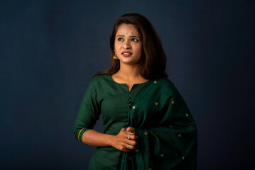 Scared beautiful female, looks nervously, afraid of something, poses against a gray background. Fear, panic, stress, and anxiety