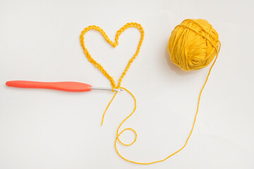 Close up of a wool ball and heart shape on white background. Heart shaped woolen yarn. Love Crochet.