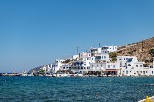 Panormos, Tinos, Greece: July 13, 2022 - Bay and village of Panormos with Cycladic houses, crystal clear water of the Aegean Sea and fishing boats on Tinos island, Cyclades, Greece