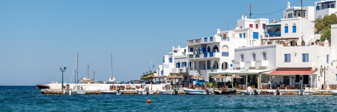Panormos, Tinos, Greece: July 13, 2022 - Bay and village of Panormos with Cycladic houses, crystal clear water of the Aegean Sea and fishing boats on Tinos island, Cyclades, Greece
