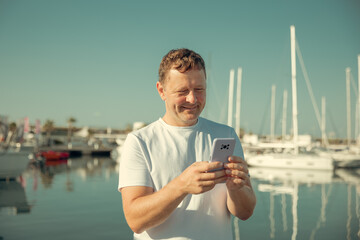 A man communicates on the phone against the background of yachts and a marina