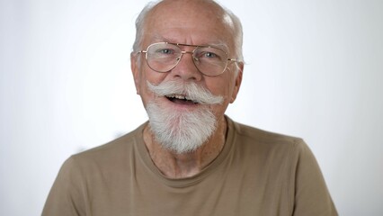 Closeup portrait of handsome old senior man smiling looking at camera against solid white background. Human emotions and facial expressions 