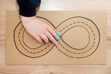 Corrugated carton race track. Boy with autism follow the lines. Implement for children or people...
