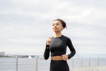 Fototapeta premium A female running athlete does cardio fitness exercises, uses a fitness watch and a tracker to measure her pulse