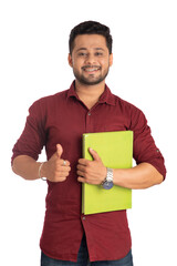Young happy man holding and posing with the book on white background.