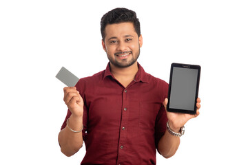 Young smiling man presenting a credit card while using a smartphone or buying online on mobile with a credit card