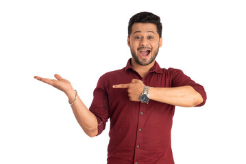 Portrait of a successful cheerful young man holding and presenting something on hand with a happy smiling face.