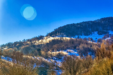 View over landscape covered with snow during sunny winter day.