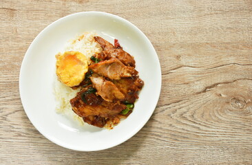 spicy stir fried barbecue pork neck with chili and basil leaf curry topping egg and rice on plate  