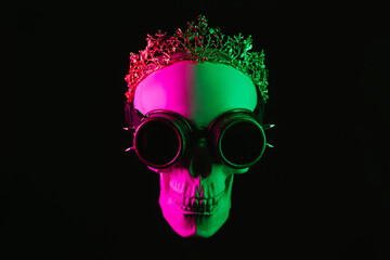 human skull in steampunk glasses and a crown with pink green light on a dark background. The...