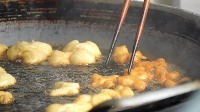B Roll slow-motion deep-fried dough stick or patongko being fried in a pan with boiling oil, Thailand street food breakfast favorite among tourists