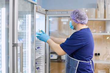 The scientist takes samples of materials for experiments out of the refrigerator