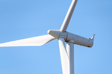 Close up of wind turbine for electricity generation against blue sky in autumn