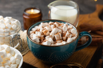 Cup of tasty cocoa drink and marshmallows in blue cup.Spices and marshmallows for winter drinks on black texture table.Winter hot drink.Hot chocolate with marshmallow and spices.Copy space.