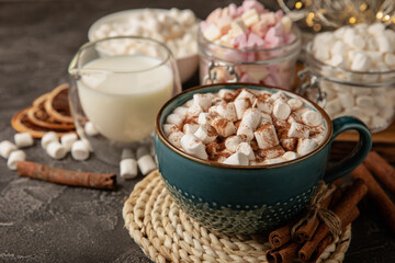 Cup of tasty cocoa drink and marshmallows in blue cup.Spices and marshmallows for winter drinks on black texture table.Winter hot drink.Hot chocolate with marshmallow and spices.Copy space.
