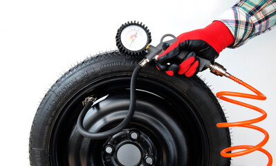 Mechanic inflates tires and checks air pressure with a pressure gauge, close-up on an isolated white background
