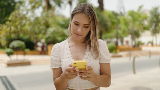 Young caucasian woman smiling confident using smartphone at street