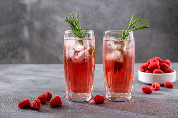 Summer refreshing alcoholic cocktails. Raspberry lemonade garnished with fresh rosemary. Summer raspberry beverage with sparkling water.  Copy space.