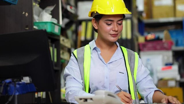 Asian Indian beautiful woman warehouse worker checking order  in desktop computer at office warehouse factory. Check emails.