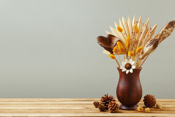 Still life with dried flowers in vase on wooden table. Autumn home decoration