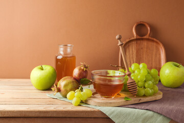 Jewish holiday Rosh Hashanah festive table setting with honey, apple and grapes over modern...